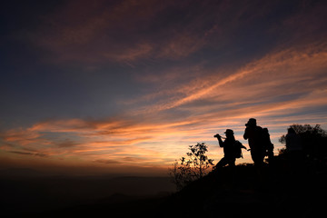 Fototapeta na wymiar Two photographers silhouette are standing on a cliff with colorful twilight sky in an evening, Thailand