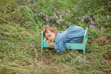 Portrait of little girl lying in small bed outside in summertime