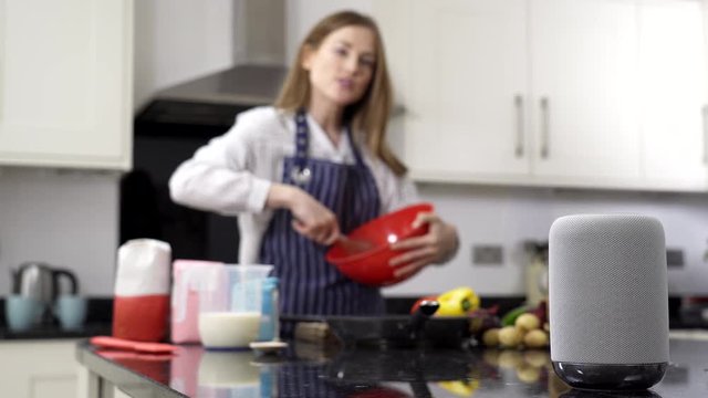 Woman Preparing Meal At Home Asking Digital Assistant Question                               