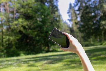 The hand of the girl holding the phone to make a photo. Photographing the meadows on a mobile phone. Relax concept.