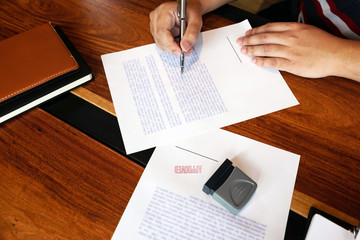 Close-up pictures of the hands of businessmen signing and stamping in approved contract forms