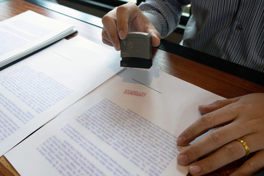 Close-up pictures of the hands of businessmen signing and stamping in approved contract forms
