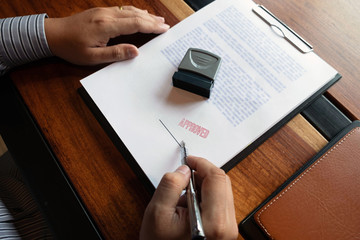 Close-up pictures of the hands of businessmen signing and stamping in approved contract forms