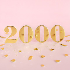 The number 2000 in golden numbers on a pink background and golden confetti. Space for text...