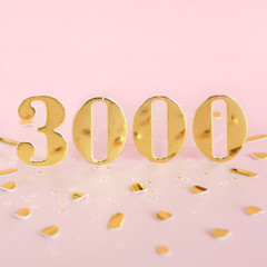 The number 3000 in golden numbers on a pink background and golden confetti. Space for text...