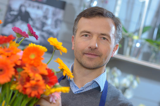 male flower seller holds flowers in his shop