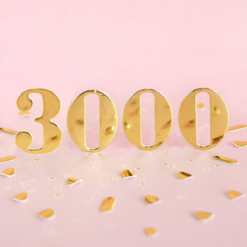 The number 3000 in golden numbers on a pink background and golden confetti. Space for text...