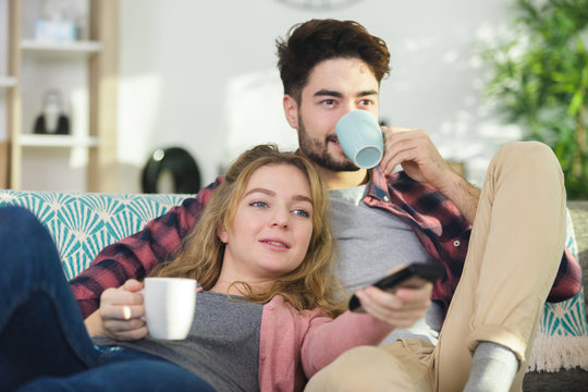picture of couple drinking warm beverage on the sofa