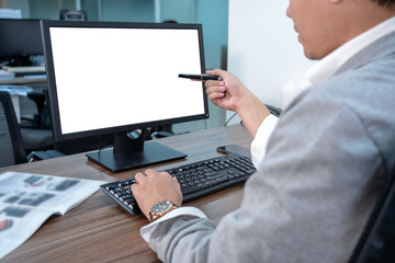 Fototapeta na wymiar Back side of Asian Businessman in formal suit using and pointing the pen to computer screen in office, business and technology workplace concept