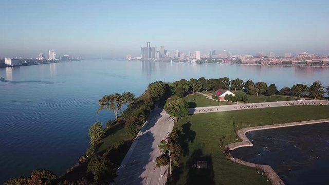 View of the Detroit skyline from Belle Isle on the Detroit river. Lake freighter passing by on a sunny summer day with blue sky. Aerial drone video of Michigan.
