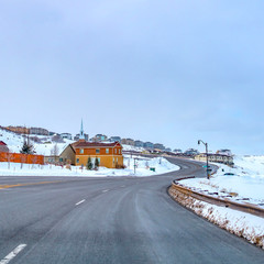 Clear Square Paved road curving through a mountain blanketed with snow in winter