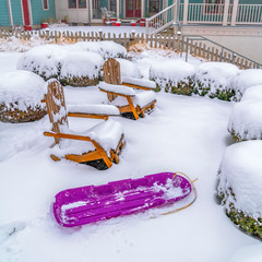 Square Purple sled wooden chairs and shrubs inside a snowy garden in Daybreak Utah