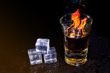 Cocktail blue burning in shot glass  with salt and lime, ice cubes on black background.
