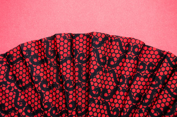 a fan with a red-black pattern lies on a pink background.Minimalism in photography