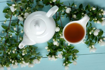 jasmine tea in a white cup, white teapot and branches of jasmine on a light blue wooden background.Organic  Herbal Bio Tea
