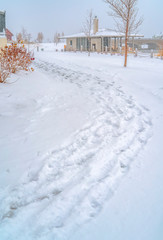 Snowy trail along Oquirrh Lake with view of a clubhouse and arched bridge