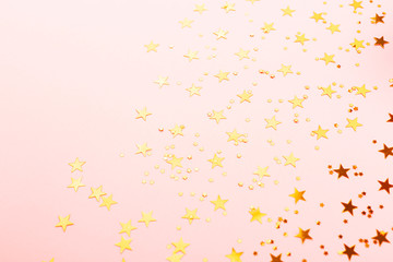 Gold star shape confetti on pink background.