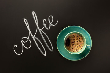 A cup of coffee on a black background. shot from the top with chalk lettering and a place for text