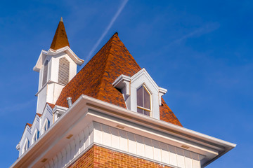 Roof and steeple of a building with vibrant blue sky in the background