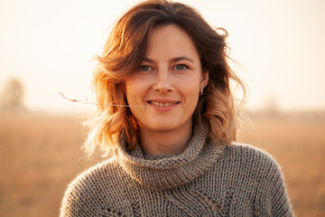 Portrait joyful young woman brunette in brown knit sweater made of natural wool and jeans having...