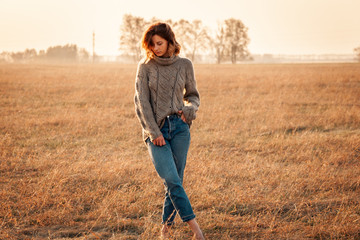 Fashion lifestyle portrait of young trendy woman dressed in brown knit sweater made of natural wool and jeans laughing, smiling, posing on the field.Portrait of joyful woman
