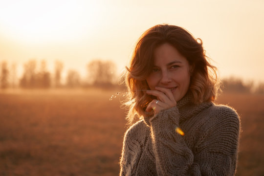 Portrait joyful young woman brunette in brown knit sweater made of natural wool and jeans having fun, smile and enjoy day on field. stylish hipster woman