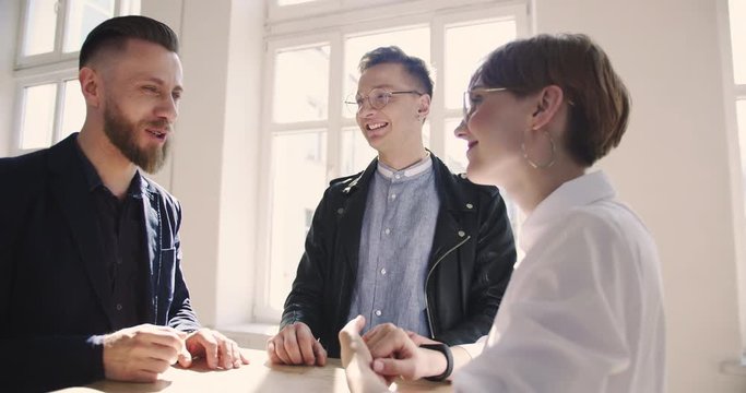 Handsome successful middle aged businessman talking to young millennial partners at comfortable light modern loft office