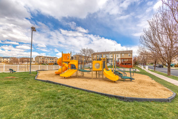 Colorful slides at a playground with homes and cloudy sky in the background