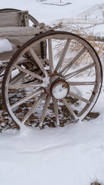 Clear Vertical Wheel of an old wooden cart against a rocky snow covered terrain in winter
