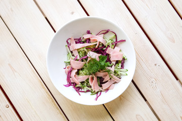Salad with red and white cabbage, fresh cucumber and slices of ham