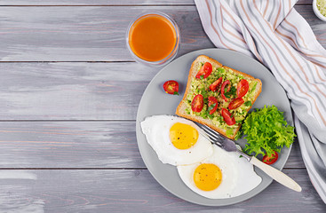 Breakfast. Fried egg, vegetable salad and a grilled avocado sandwich on a grey background. Top view
