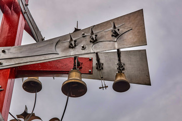 Column with vintage bells for alert on the railway station on the background of a cloudy sky