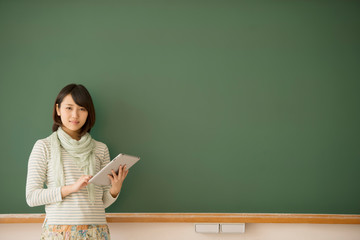 黒板の前で微笑む大学生