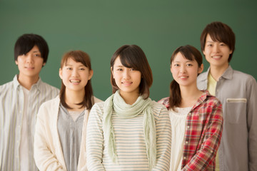 黒板の前で微笑む大学生