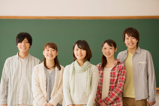 黒板の前で微笑む大学生