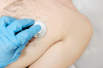 Hand in a blue glove with a stethoscope listening. Nurse's medical procedure. The concept of...