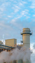 Obraz premium Vertical Cloudy blue sky viewed behind the towers and buildings of a Power Plant