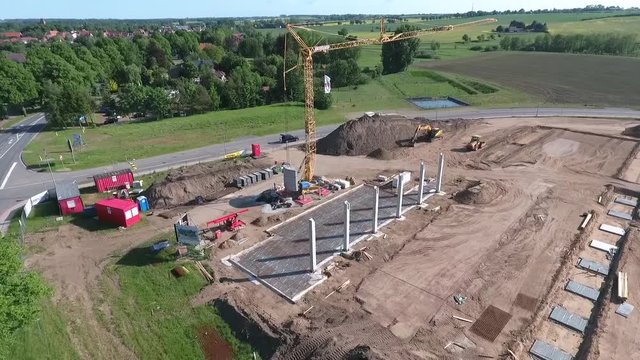 A drone flies over a large construction site on which a huge production hall is being built.