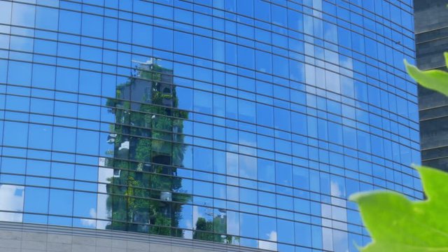 Reflection inside a modern building, showing Bosco Verticale in Milan. Green city concept and ecology friendly.