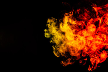 Beautiful horizontal column of smoke in the neon bright light of red, green, yellow and orange on a black background exhaled out of the vape. Nice pattern for printing and backdrop of colored waves.