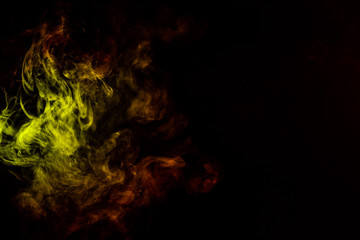 Fototapeta premium Beautiful horizontal column of smoke in the neon bright light of red, green, yellow and orange on a black background exhaled out of the vape. Nice pattern for printing and backdrop of colored waves.