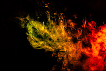 Obraz na płótnie Canvas Beautiful horizontal column of smoke in the neon bright light of red, green, yellow and orange on a black background exhaled out of the vape. Nice pattern for printing and backdrop of colored waves.