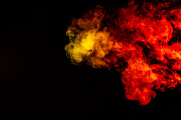 Beautiful horizontal column of smoke in the neon bright light of red, green, yellow and orange on a black background exhaled out of the vape. Nice pattern for printing and backdrop of colored waves.