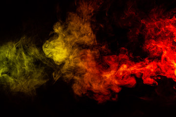 Fototapeta na wymiar Beautiful horizontal column of smoke in the neon bright light of red, green, yellow and orange on a black background exhaled out of the vape. Nice pattern for printing and backdrop of colored waves.