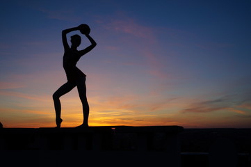 dancer in the dance does the splits in the air against the sunset.