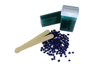 Top view hair removal depilation concept. Green aloe wax cartridge and violet granules with wood spatula isolated on white background.