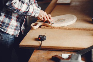 Obraz na płótnie Canvas A man carves a tree. The carpenter works in a studio. An engineer provides a tree shape