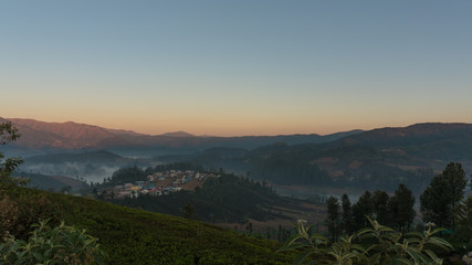 dramatic sunrise over the Emerald lake in Ooty with mountains in the background and mist covering the lake on a cold early morning, India. Top view of Emerald lake and village.