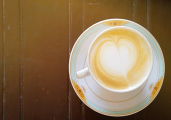 Cup of hot latte art coffee on wooden table.