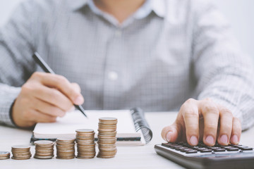 close up hand business man accounting calculate calculator expenses with savings money coins...